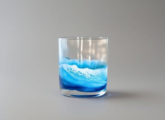 Glass tumbler with blue wave design on a neutral background