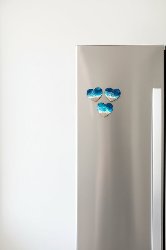 Stainless steel refrigerator with decorative blue ocean resin heart-shaped magnets.
