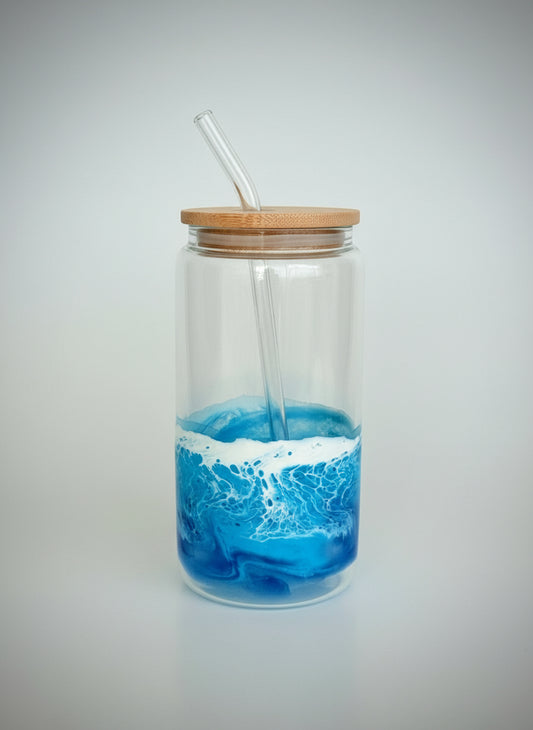 Clear glass jar with blue ocean design and wooden lid on a white surface.