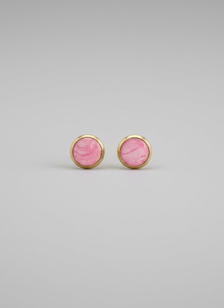 Pair of pink earrings with gold rims on a gray background