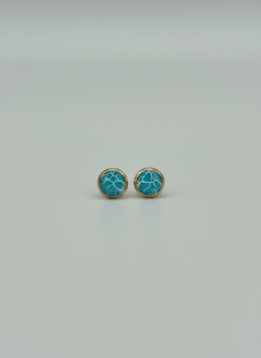 Pair of turquoise earrings with gold accents on a light gray background