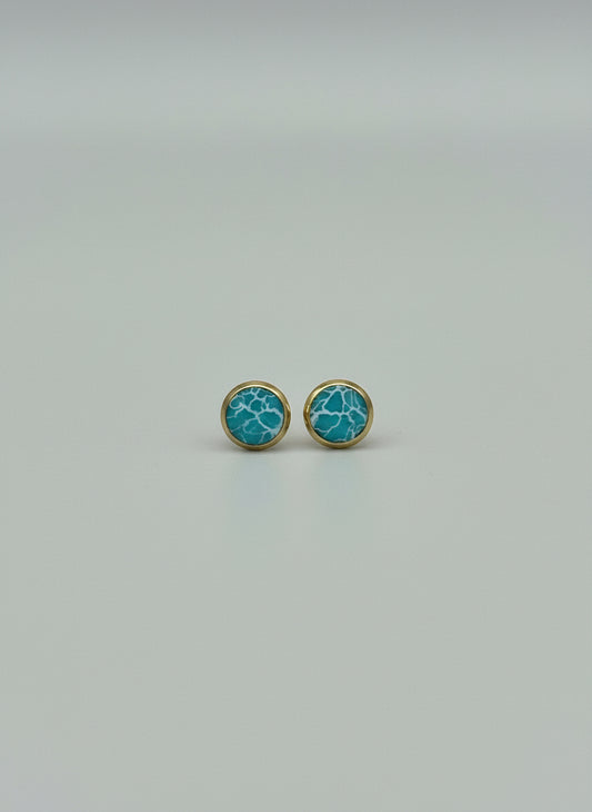 Pair of turquoise earrings with gold accents on a light gray background