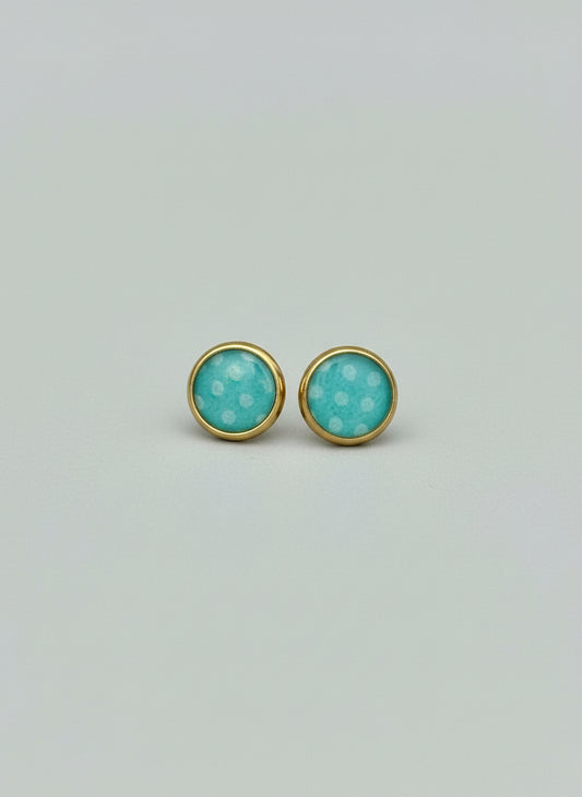 Pair of turquoise earrings with gold accents on a light gray background