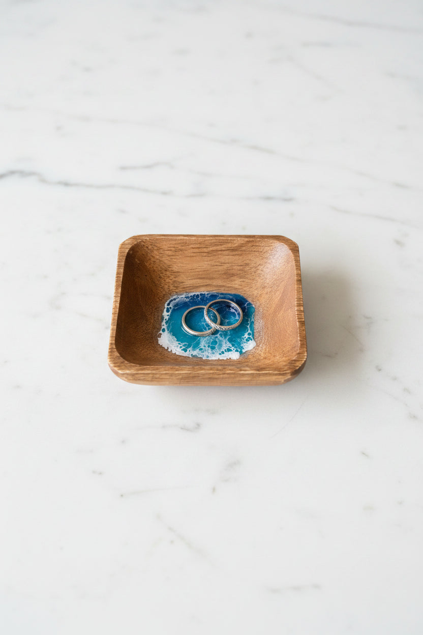 Wooden bowl with blue and white resin wave design on a concrete surface