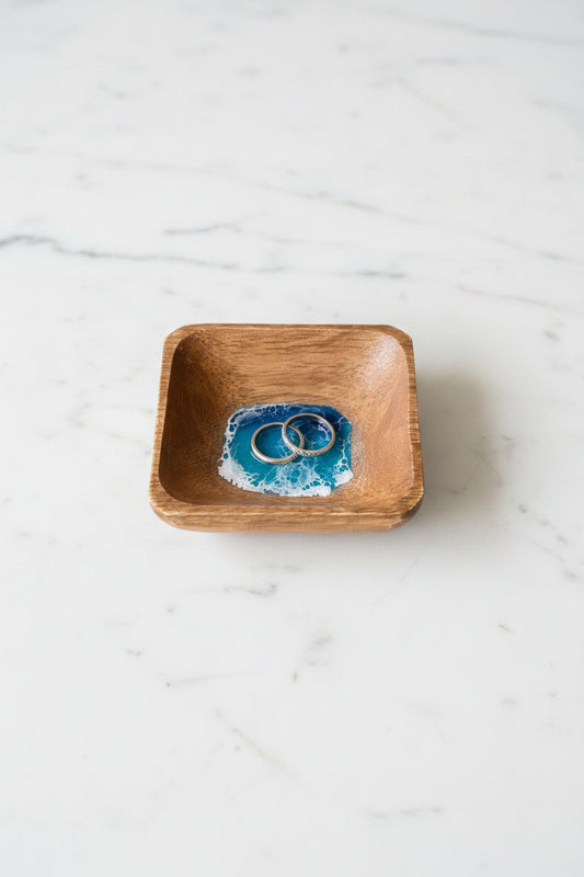Wooden bowl with blue and white resin wave design on a concrete surface