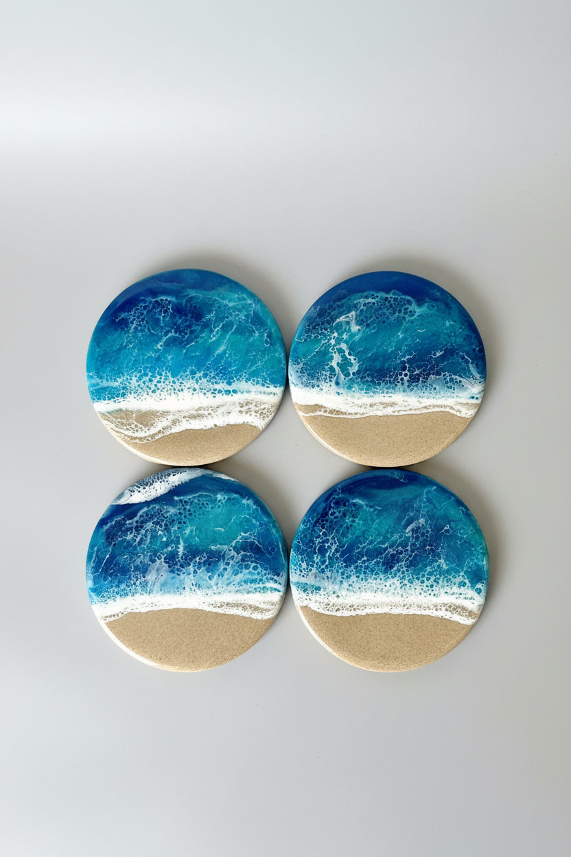 Four round coasters with blue resin wave design on a gray background