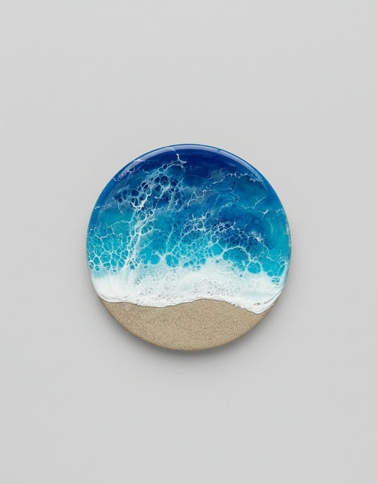 Round coaster with resin ocean design on a gray background