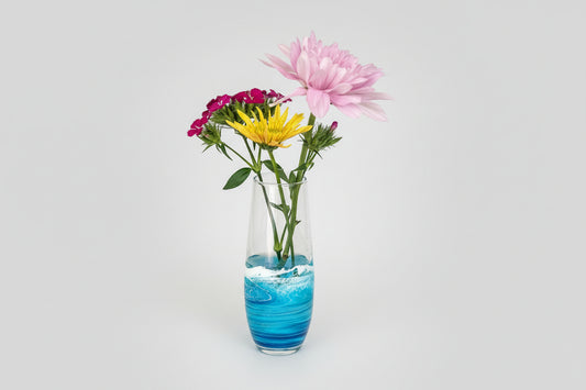 Vase with blue resin wave design and colorful flowers on a light gray background
