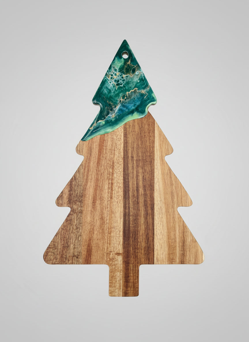 Wooden cutting board shaped like a Christmas tree with a green resin top on a light gray background