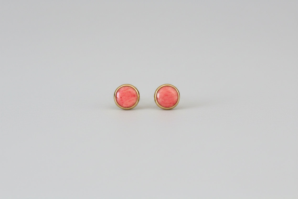 Pair of pink round earrings on a light gray background