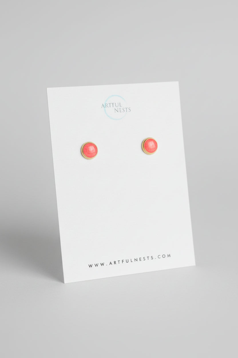Pair of red earrings on a white card with 'Artful Nest' branding on a gray background